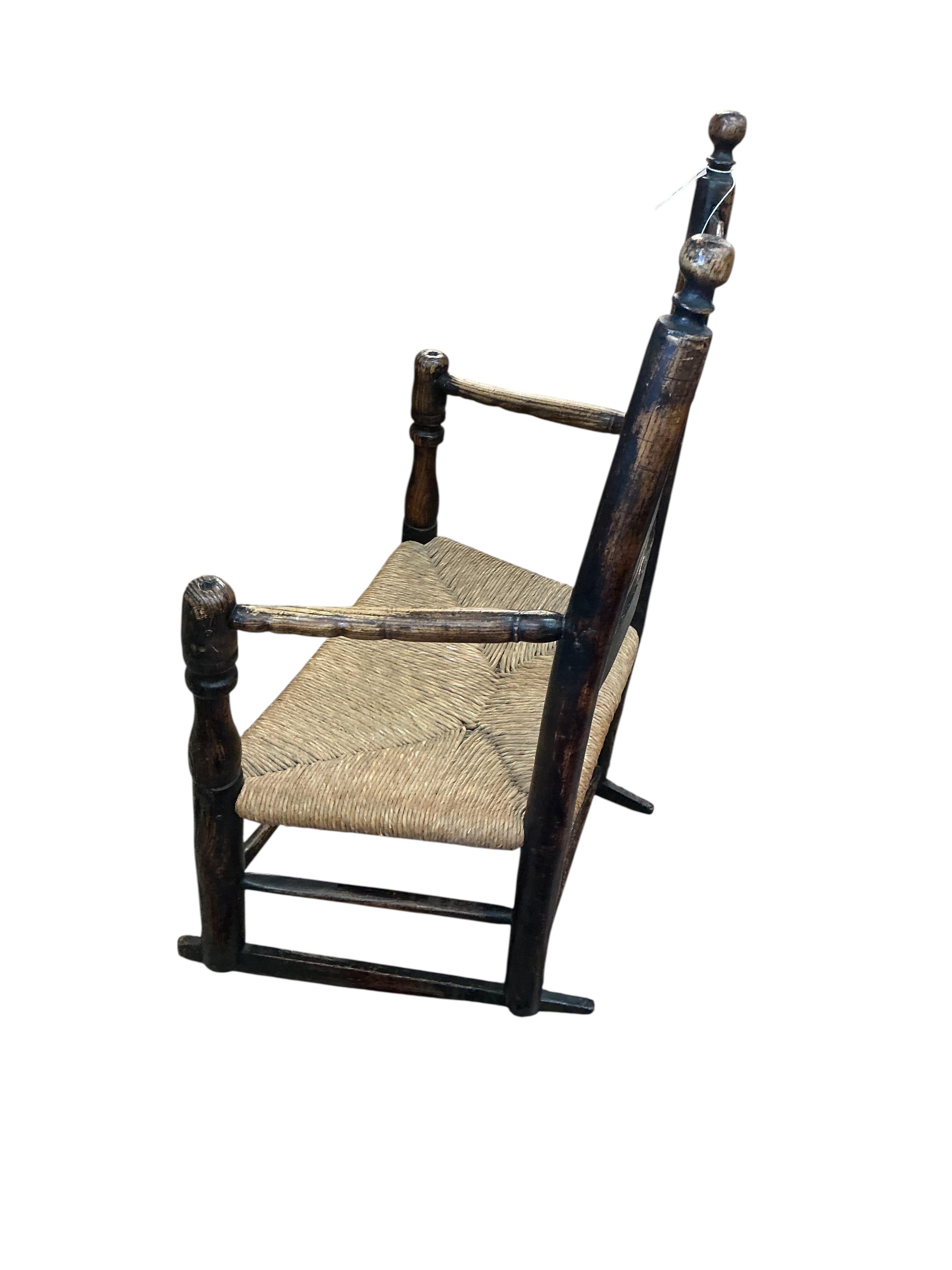 An early 19th century Provincial ash rush seat ladderback rocking chair, width 64cm, depth 41cm, height 95cm